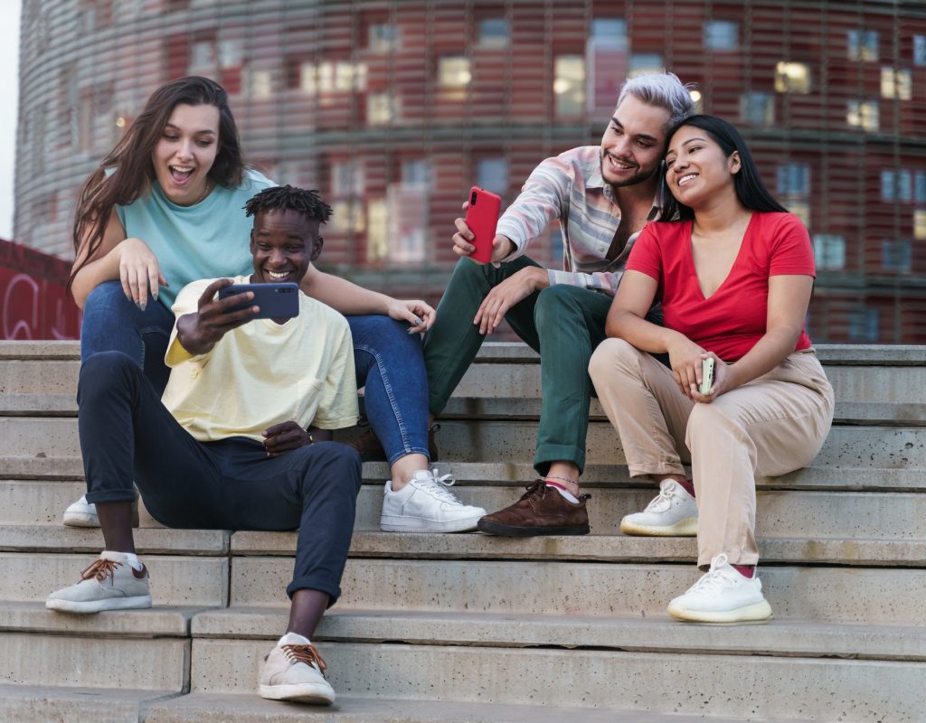 Group of happy multi ethnic friends taking selfies sharing social media content on smart phone