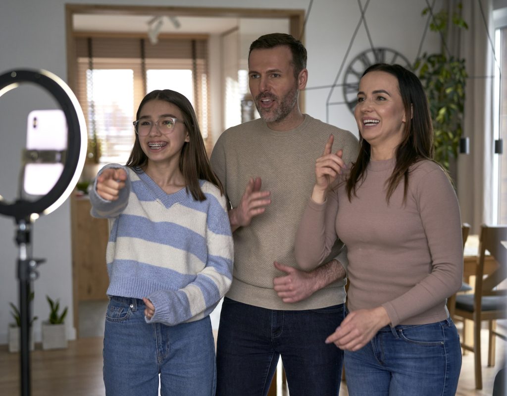 Teenager girl with parents recording dancing for social media