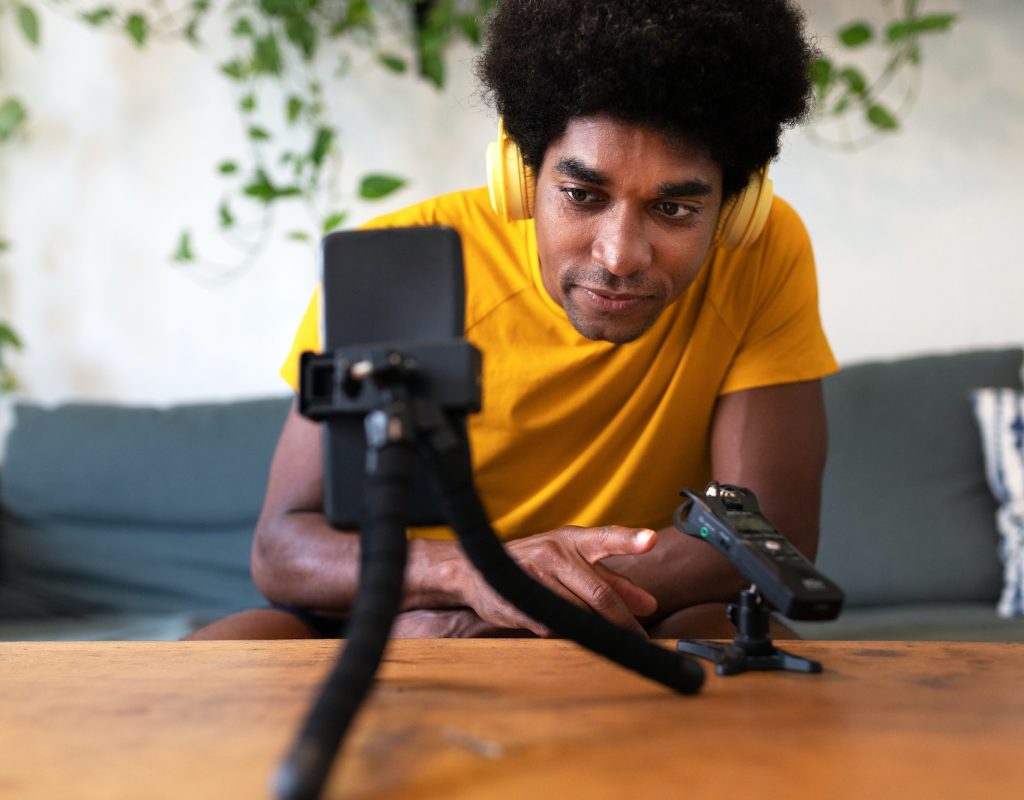 Young african american man recording himself for social media network checking the recorder.